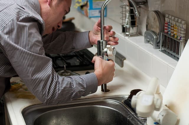 A plumber repairing kitchen faucet tap