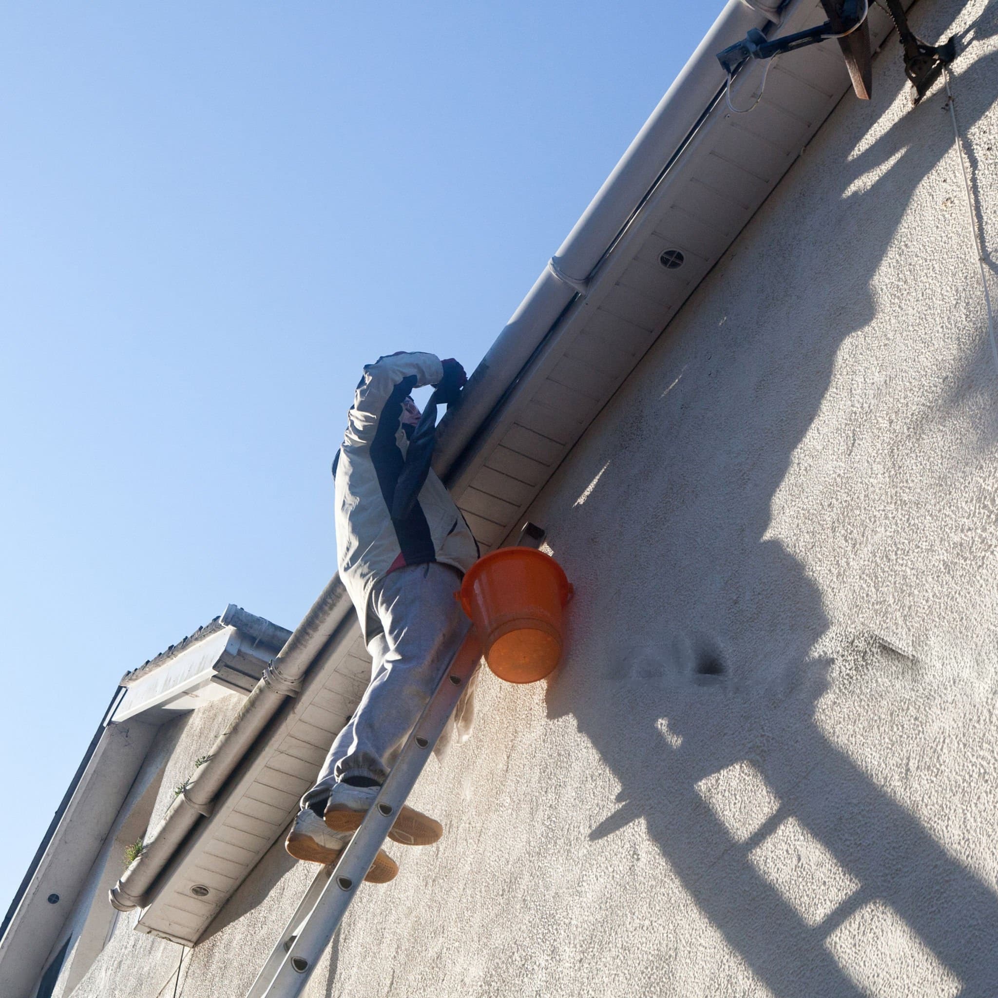 A worker cleaning gutters downpipes